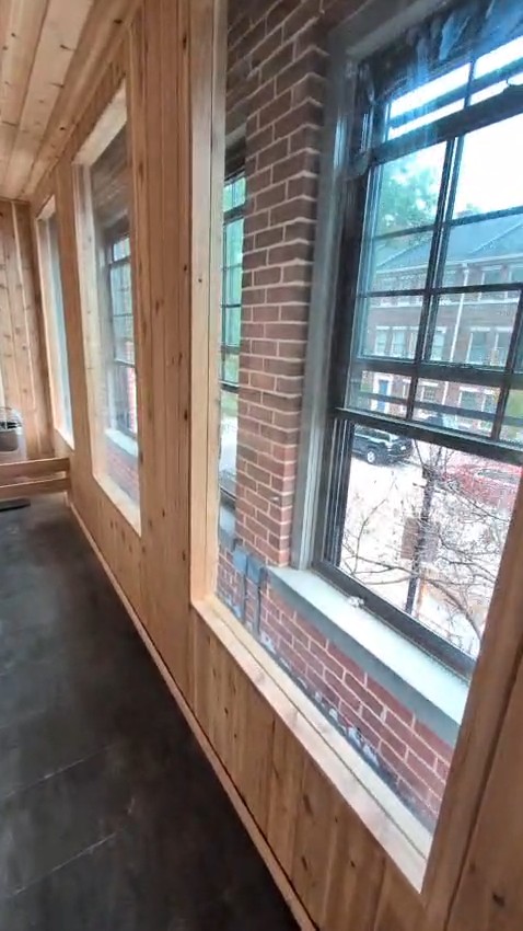Long indoor sauna with wood-paneled walls, tall windows in deep brick reveals and the heater at the far end